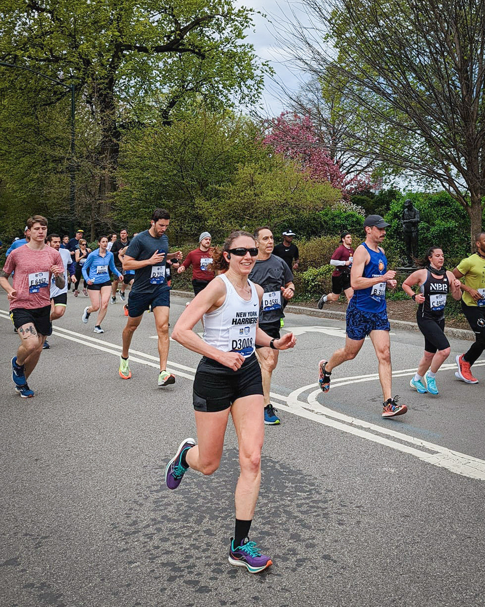 Smiling woman in sunglasses running a race.